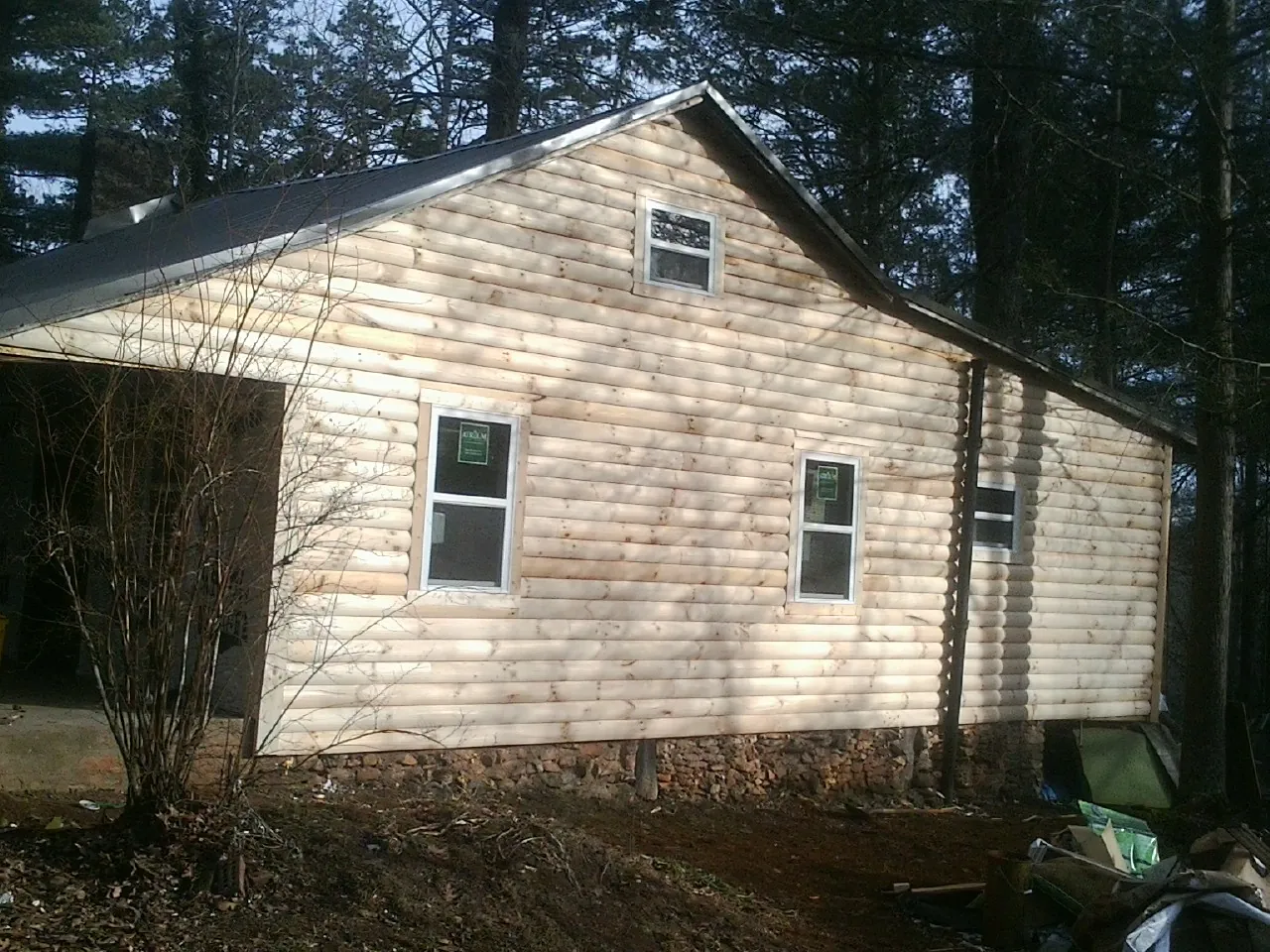 New log siding and dark metal roofing on a gable end in Shorter