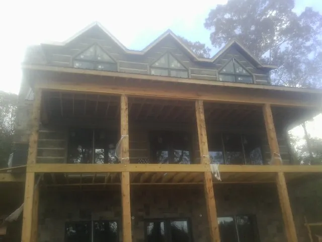 Dormers and porch framing on a large log home under construction — Roof Coating work by our crew in Shorter