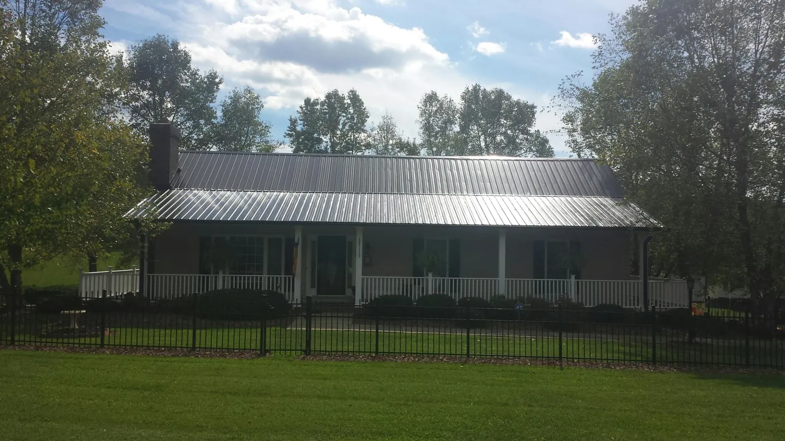 Gray metal roof on a brick ranch with a full width front porch — Gutter Guard Installation work by our crew in Shorter
