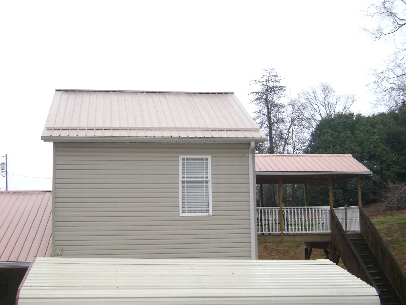Tan metal roofs on a two story addition and attached porch, from a Roof Replacement job in Shorter