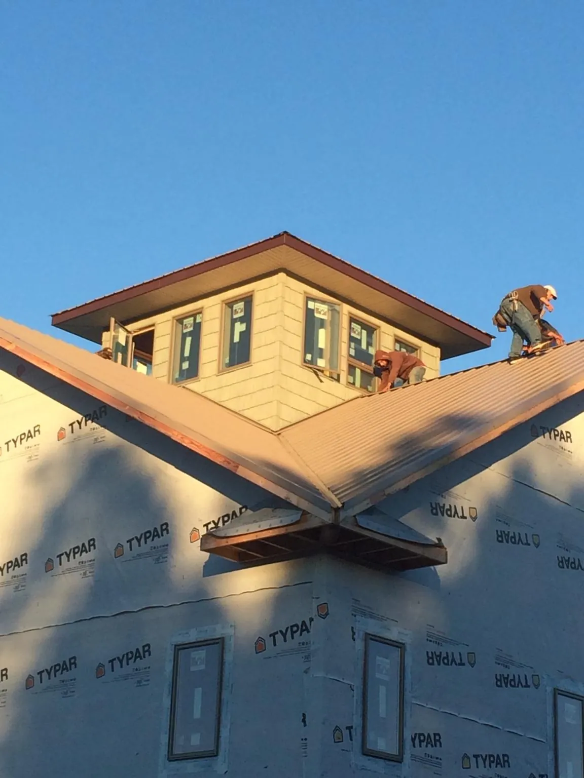 Roofers working around a rooftop cupola on a new metal roof at sunset — Roof Waterproofing in Shorter by Roofing Brothers
